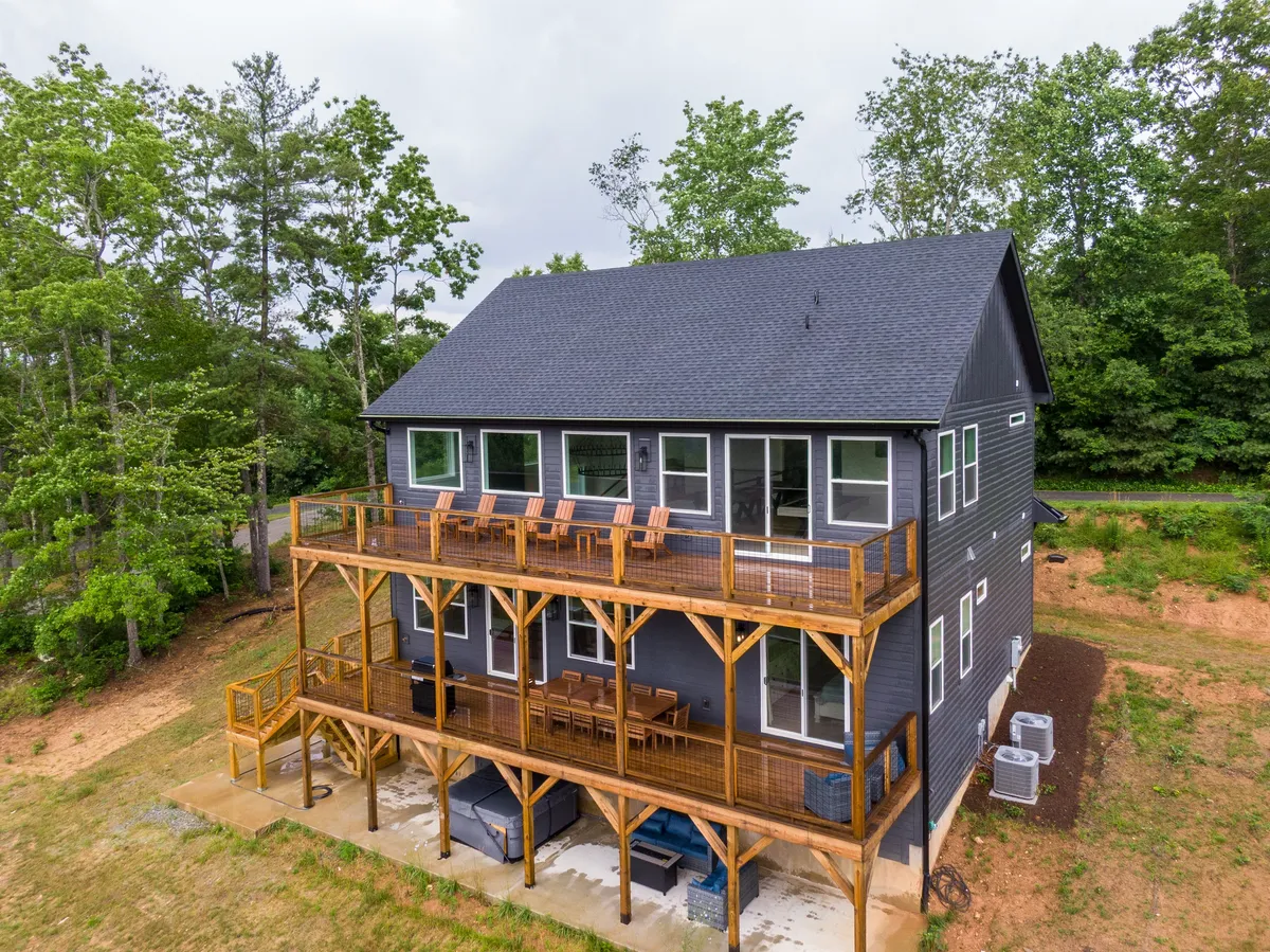 A wide view of two large decks with wooden railings, surrounded by trees and modern architecture. The decks offer space for gatherings, celebrations, and seamless access to the natural beauty of the mountains.