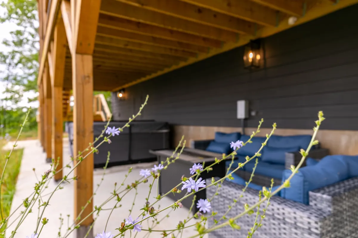 A tranquil outdoor seating area adorned with vibrant purple flowers and a grill, offering a welcoming setting for socializing, sharing meals, or relaxing after a productive day. The patio faces scenic outdoor views, reinforcing the retreat’s connection to nature.