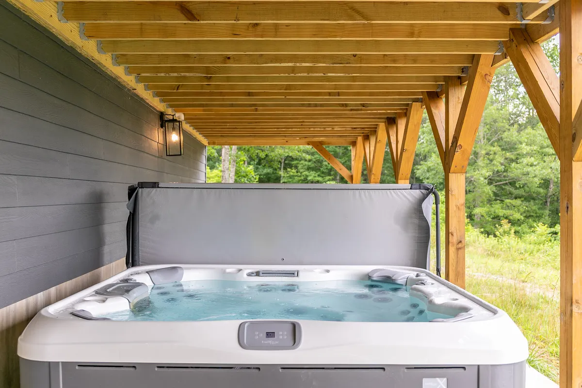 An inviting hot tub set within a wooden structure, surrounded by lush greenery. The tranquil atmosphere is perfect for unwinding after a day of outdoor activities, blending relaxation with immersion in the natural environment.